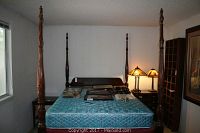 Full view of four poster bed with mattress, box spring, and accessories on top.