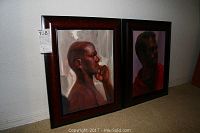 Two original framed portraits by Jane Ford side by side on carpet against a wall