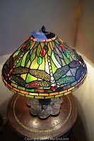 Front view of Tiffany-style stained glass shade with dragonfly motif, illuminated