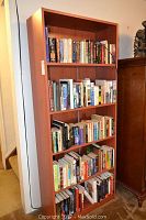 Full view of the brown wooden five-shelf bookcase mostly filled with books