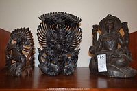 Three carved wooden Buddhist figures displayed side by side showing entire lot