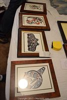 Four framed lithographs laid out on a surface showing design and frame style