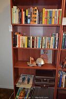 Full view of bookcase with three shelves containing books, magazines, and decorative items