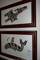 Two framed lithographs hanging on wall, one above the other