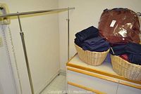 Metal rolling garment rack with baskets and linens on dresser, shows wear and rust