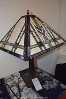 Side view of one Tiffany style table lamp showing stained glass shade with geometric patterns in pastel hues and metal base.