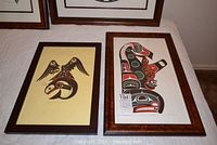 Pair of two framed lithographs lying on a white cloth surface, showing both artworks.