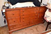 Front view of the wood dresser showing nine drawers with round wooden knobs and items placed on top.