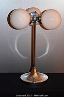 Full view of vintage lamp from the front showing three white opaque glass globes and chrome base and stem against a light background.