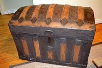 Full view of humped steamer trunk showing wood slats and embossed tin panels