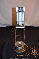 Full front view of the metal desk lamp with glass bulb housing, tubing socket, and cord visible.