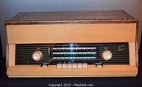 Full view of tube radio with wooden cabinet, showing front panel with volume and tuning knobs, button presets and dial.