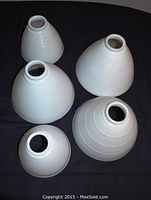 Five milk glass conical diffusers arranged on black surface