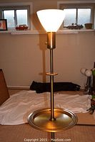 Full view of the vintage torchiere floor lamp showing height, metal tray base, and white glass diffuser lit.