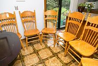 Six replica press back solid pine chairs grouped together showing the finish and design.
