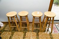 Four pine stools arranged in a row showing overall appearance and height.