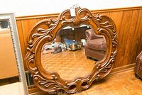 Front view of the ornate round wooden carved frame mirror showing its size and reflective surface.