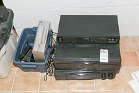 Photo showing three black audio components stacked: a graphic equalizer on top, dual cassette tape deck below, and receiver at the bottom with wires and remote in plastic bin to the side.