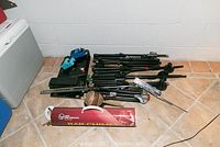 Overview of six microphone stands, three foot pedals, LP bar chimes and a maraca on floor tile