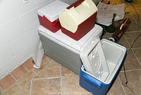 Four coolers stacked together: a large grey cooler at bottom, blue cooler with open lid on the side, and two smaller red/white coolers on top.