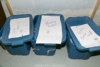 Three blue plastic bins each labeled for educational content: Science Books, Reading Books, and English Junior Level