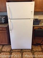 Front view of white Frigidaire refrigerator showing top freezer and bottom fridge doors, in kitchen setting.