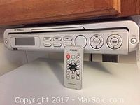 Front view of Curtis DVD player with control buttons, display screen and remote placed in front.