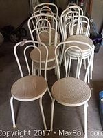 Photo of 16 white plastic chairs stacked and grouped, showing front and back views.