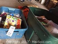 Two large plastic bins filled with children's reading books and educational games in a garage setting.