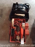 Photo showing orange Black and Decker work wheel with various attachments and red cords in a red tray.
