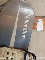 Millennium snowboard top with attached snowboard boots visible showing brand and condition.