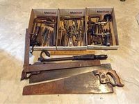 Overall view of boxes with assorted drill bits, chisels, clamps and hand saws