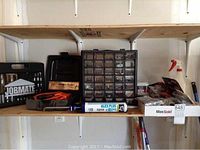 Shelf holding the lot items including the Jobmate socket set, the plastic hardware organizer, caulking gun, and other tools.