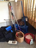 Lot of cleaning tools, bags, basket, and storage items arranged on floor against wall.