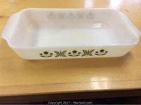 Top-down view of the rectangular opaque white glass baking dish showing the green floral pattern on the inside side walls and built-in handles.