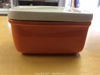 Side view of the rectangular butter dish showing orange base and white lid.