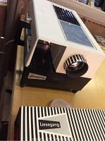 Front and side angled view of the Liesegang projector showing the focus dial, casing details, and brand label on black base.