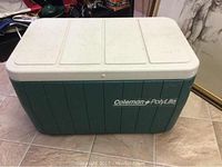 Front view of green and white Coleman Polylite cooler with segmented lid and logo.