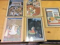 Six framed Japanese story prints under glass, laid out on a wooden surface.