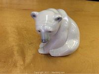 Front top angle view showing detailed face and posture of the ceramic polar bear figurine on wood table.