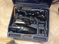 Top view of open plastic carrying case with four blue and black cordless power tools inside: circular saw, drill, sander, and vacuum, all battery operated.
