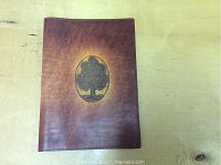Front view of the brown leather book cover with embossed tree design.