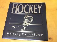Front cover of the black hockey card album with the word HOCKEY and Hockey Card Album text in silver lettering, showing the binder itself.