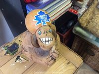 Front and top view of the ceramic gorilla piggy bank featuring a Toronto Maple Leafs leaf on its head, showing the facial details and logo.