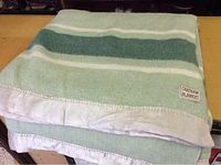 Folded vintage blanket showing green and white horizontal stripes with sewn Chatham Blanket label at one corner.