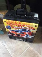 Photo of front and side of Hot Wheels carrying case featuring orange sports car graphic and logo