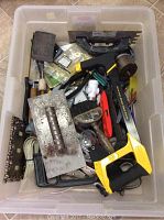 Top view of the box lot showing various hand tools mixed together in a plastic tote including saw, trowels, pliers, brush, level and clamps.