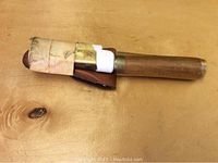 Top image showing survival saw with wooden handle wrapped partially in tape, with leather pouch attached.