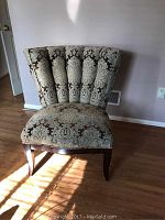Front view of a Schnadig wing chair with patterned fabric and wooden legs, showing condition and design details.