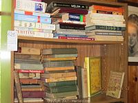 Wide view of two shelves on a wooden bookshelf showing multiple vintage hardback books related to grammar, writing, and foreign languages including Welsh and Spanish. Books have visible wear and aged bindings.